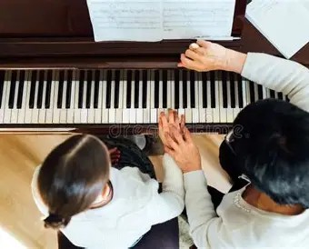 piano teacher and student sitting at a piano